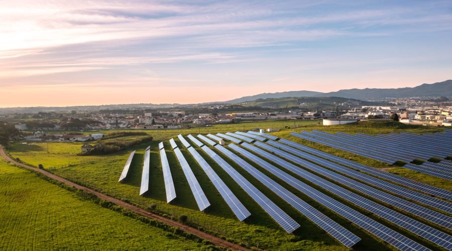 Aerial drone shot of rows of solar panels in lush fields showcase green energy innovation, harmonizing with nature for sustainable electricity under sky.